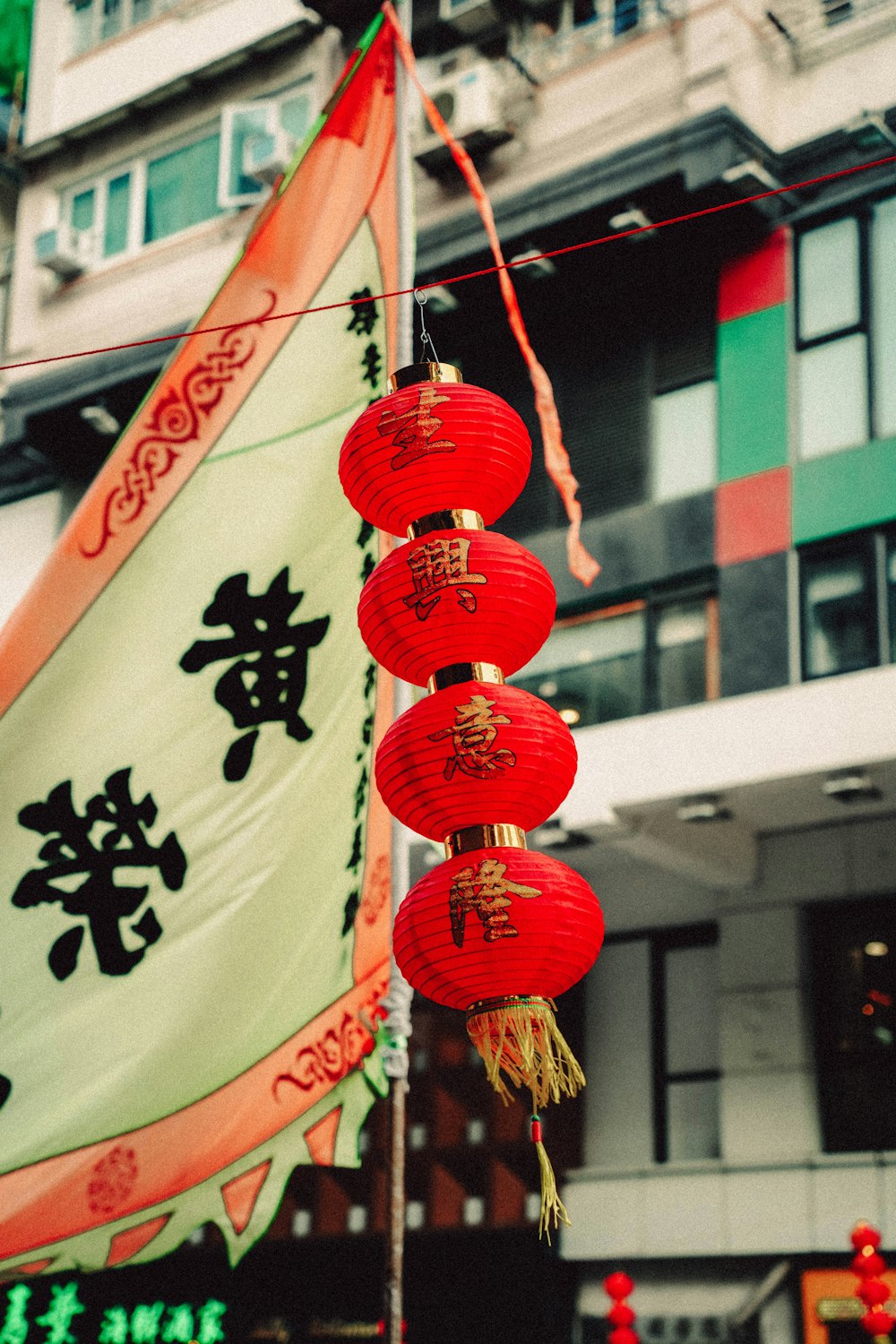 red lanterns hanging from a pole in front of a building