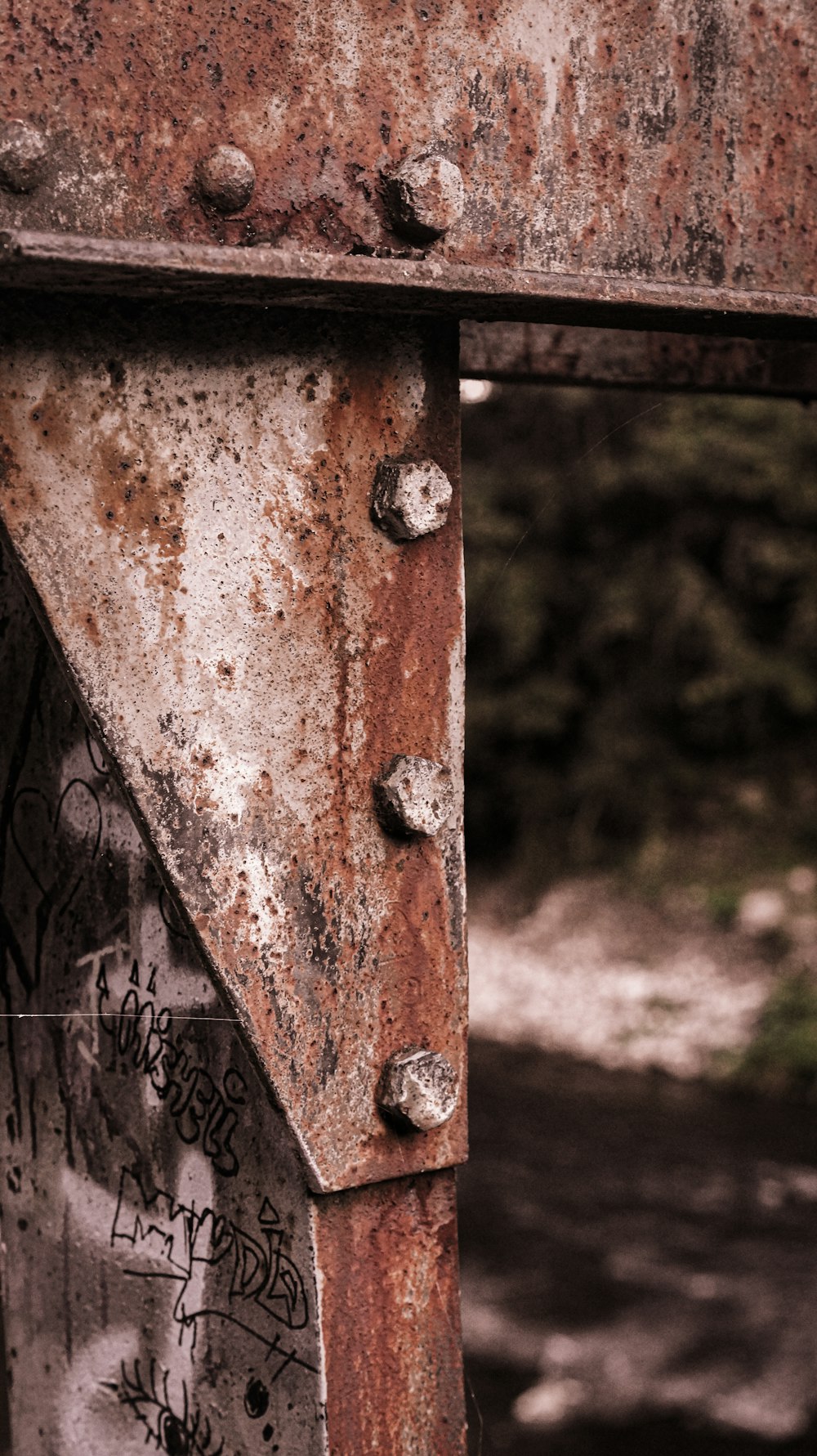 a rusted metal structure with lots of graffiti on it