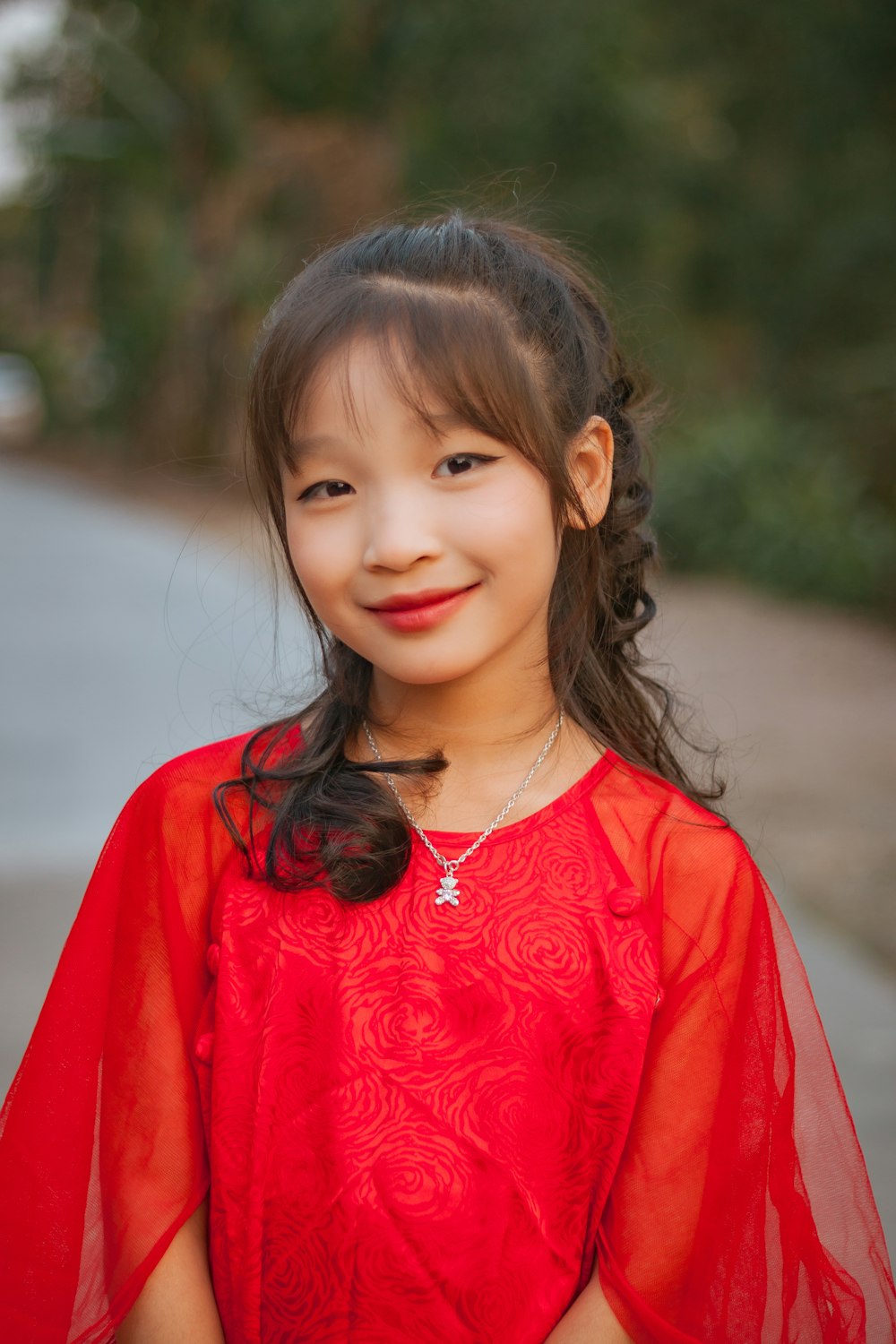 a young girl in a red dress smiles at the camera