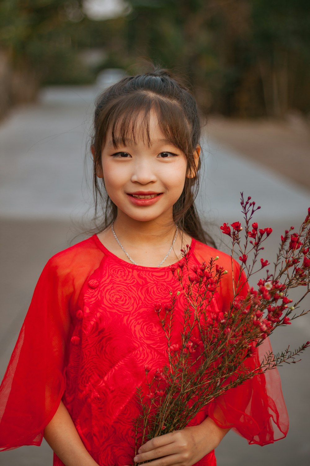 a girl in a red dress holding a bouquet of flowers