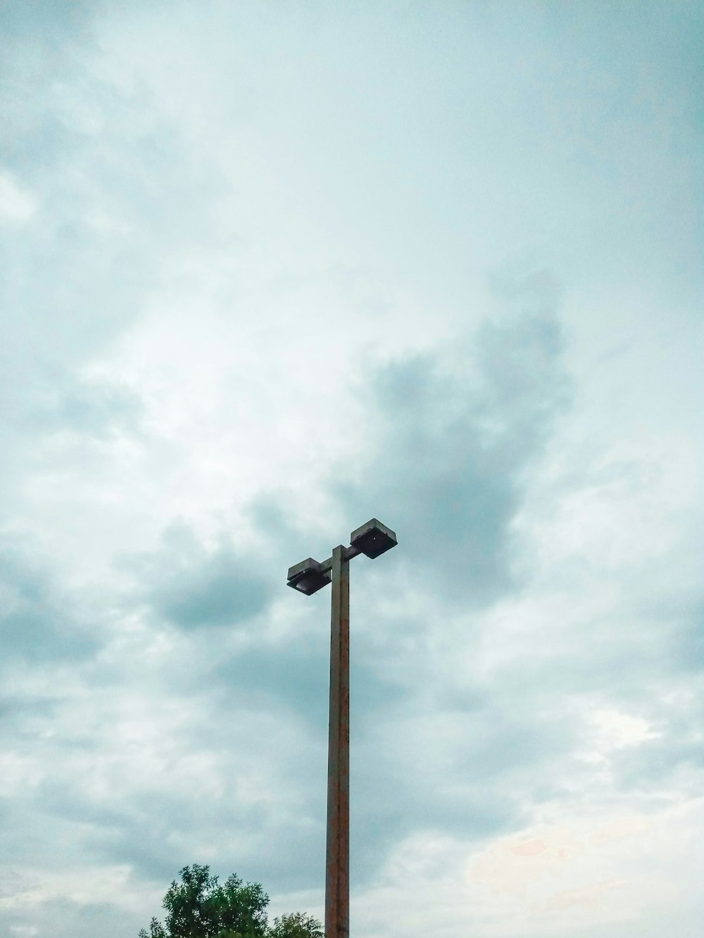 a street light on a pole with a cloudy sky in the background