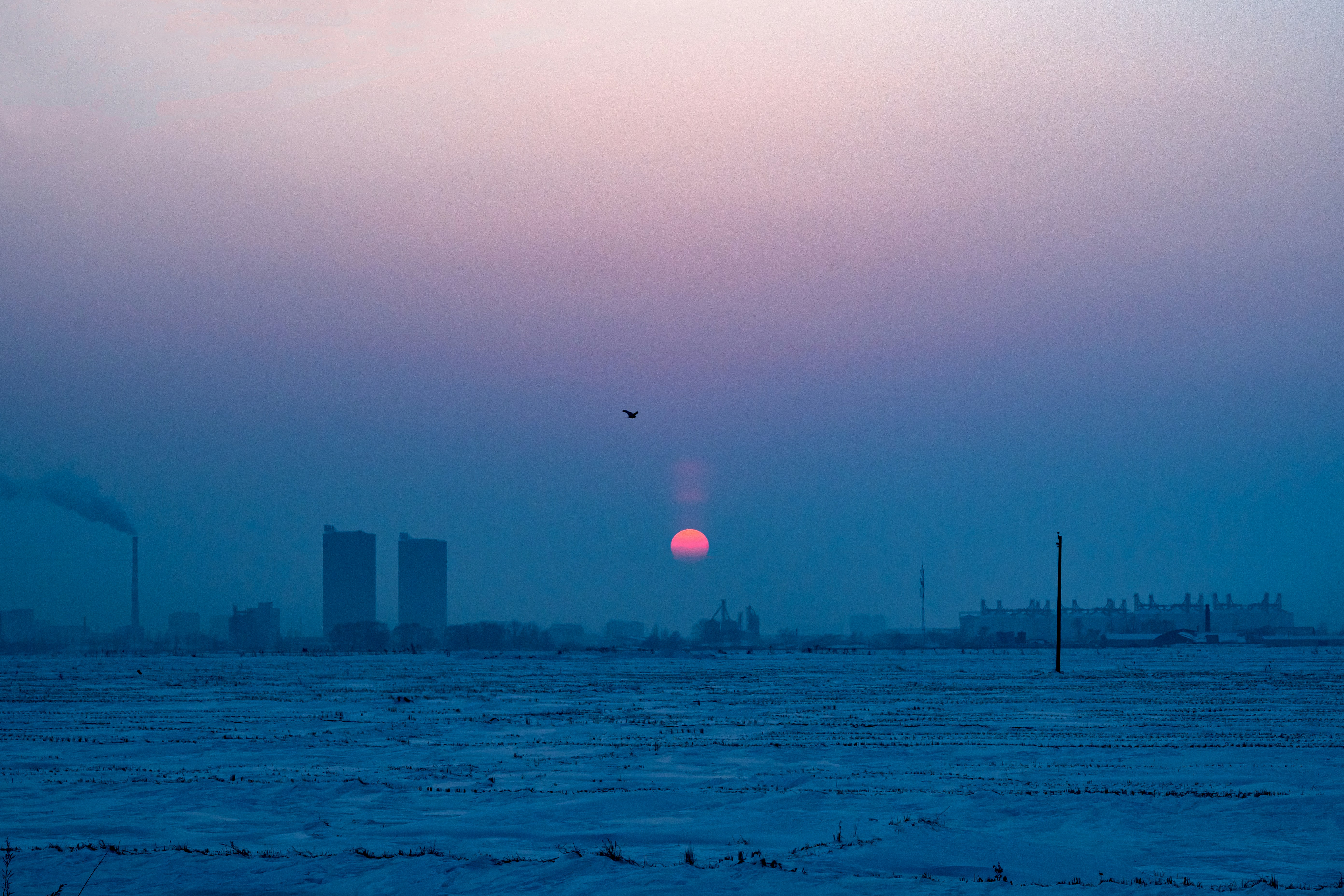 the sun is setting over a snowy field