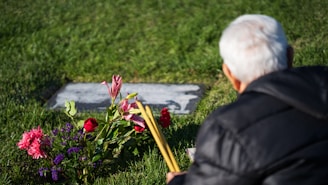 a man sitting in the grass next to flowers