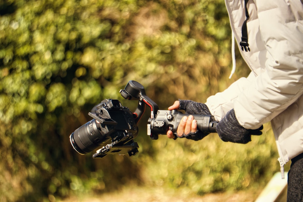 a person holding a camera and a tripod