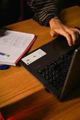 a person typing on a laptop on a wooden table