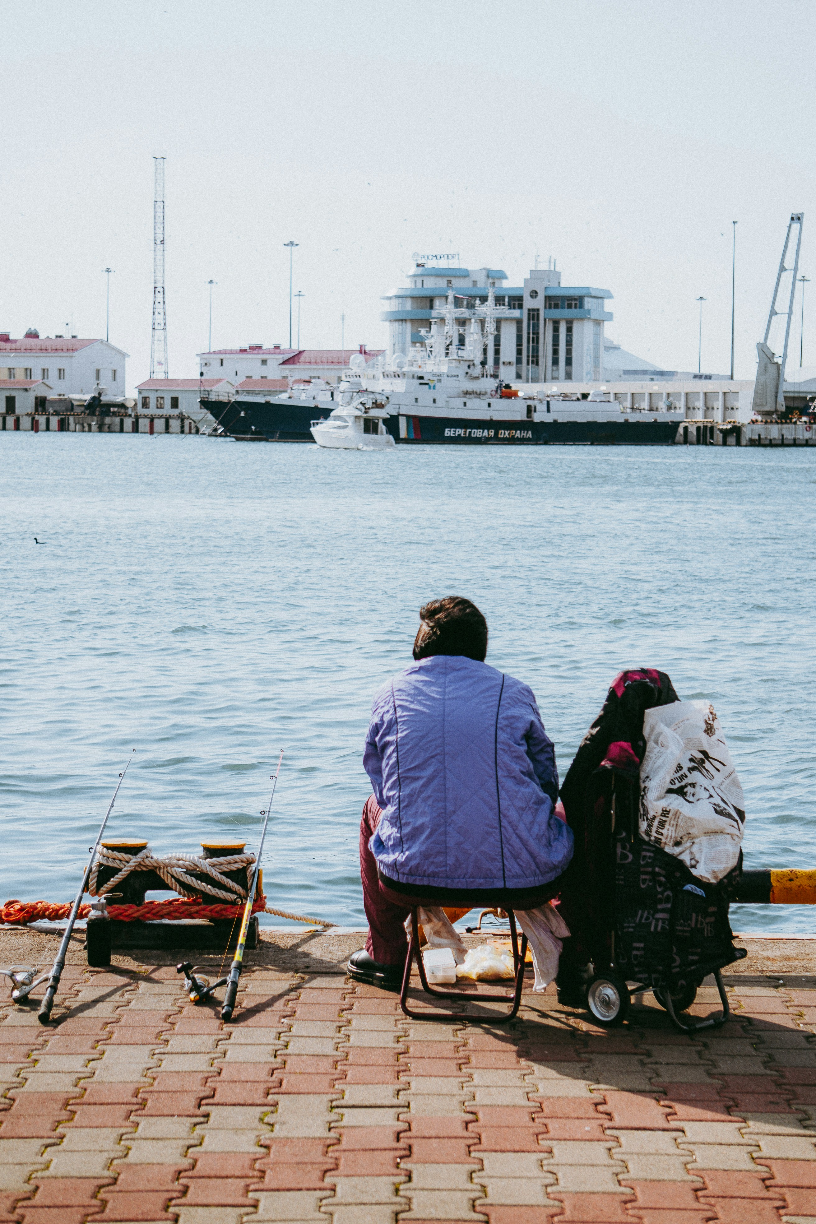 A couple of people sitting on a bench next to a body of water photo ...