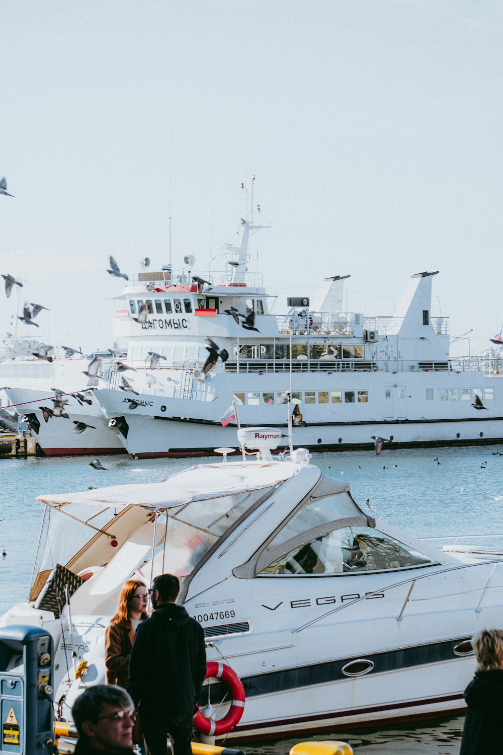 a group of people standing next to a white boat