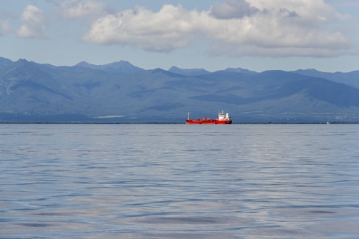 a large red boat floating on top of a large body of water