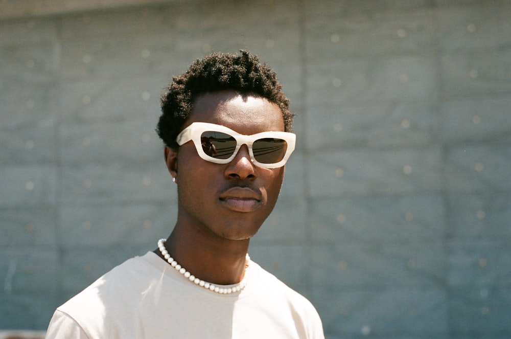 a man wearing sunglasses and a pearl necklace