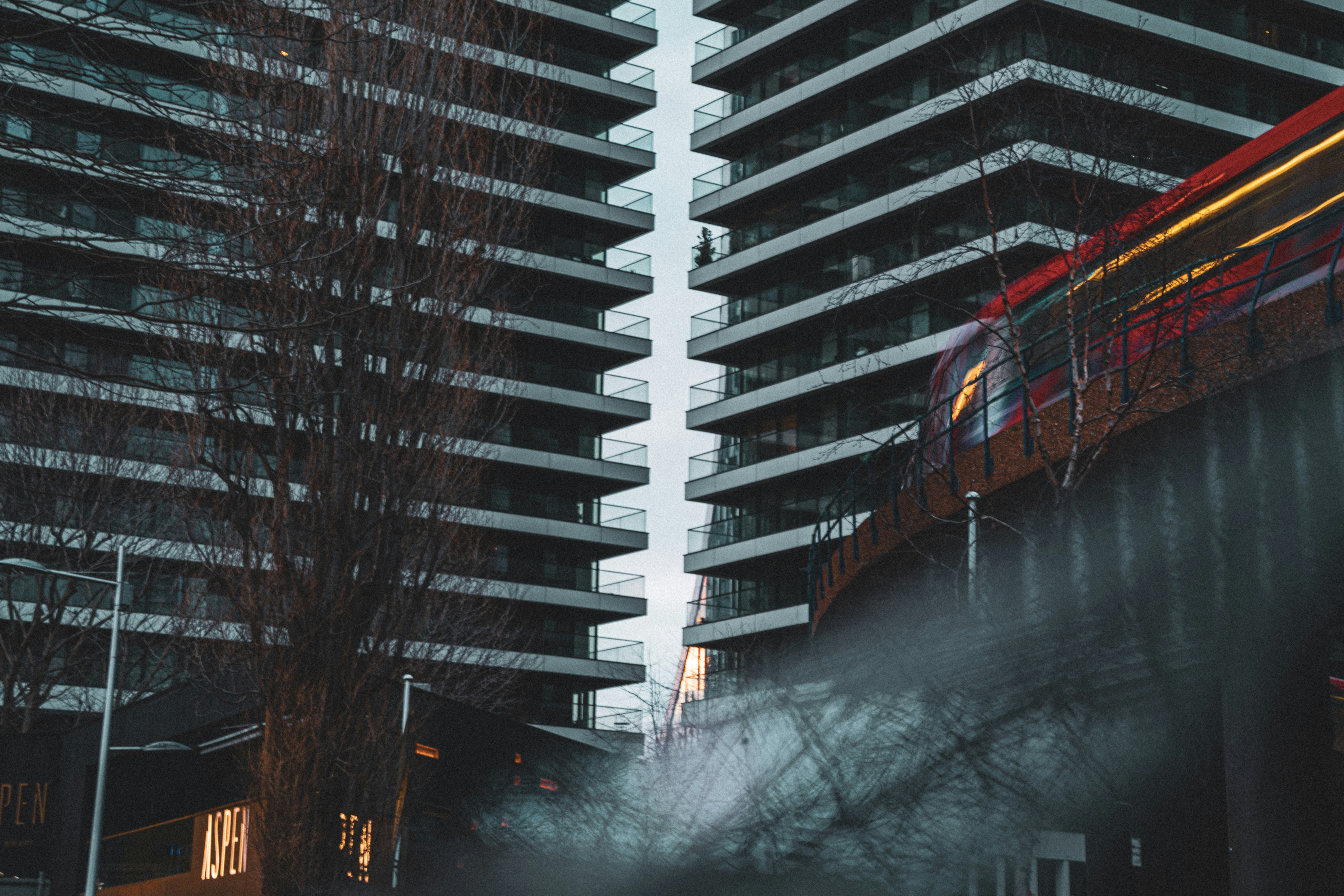 a red train traveling past tall buildings in a city