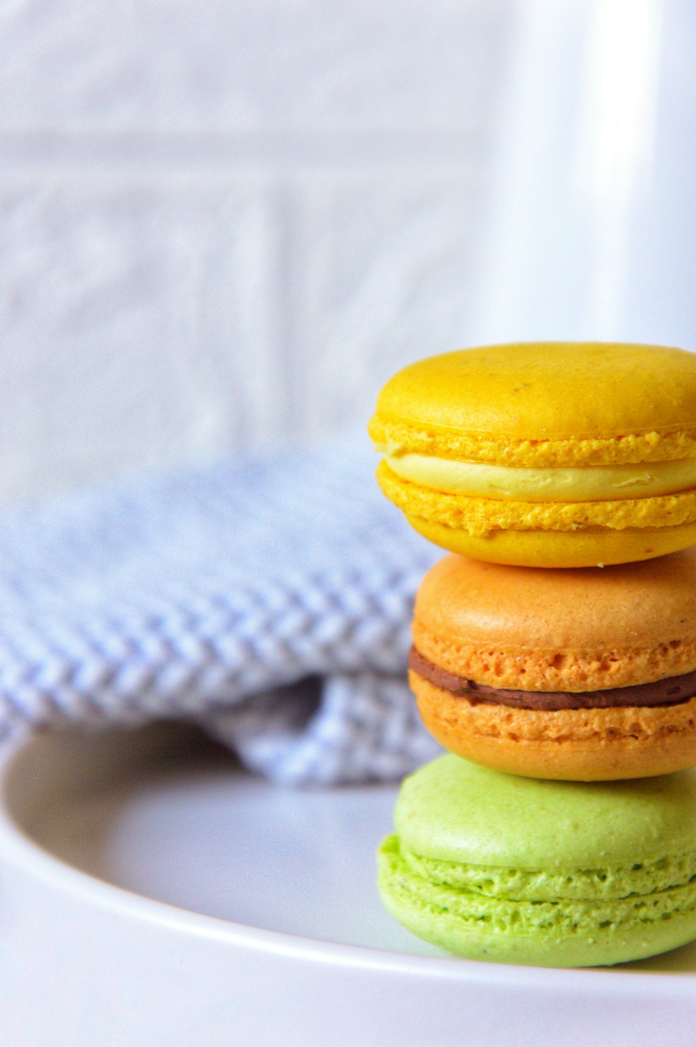 a stack of three macaroons sitting on top of a white plate