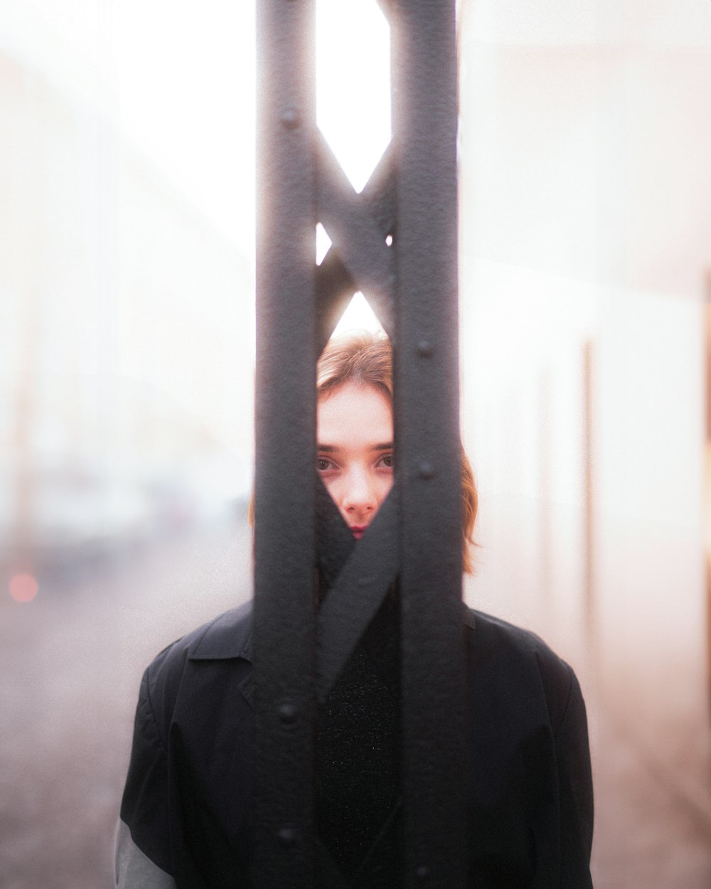 a woman standing behind a metal gate with a surprised look on her face