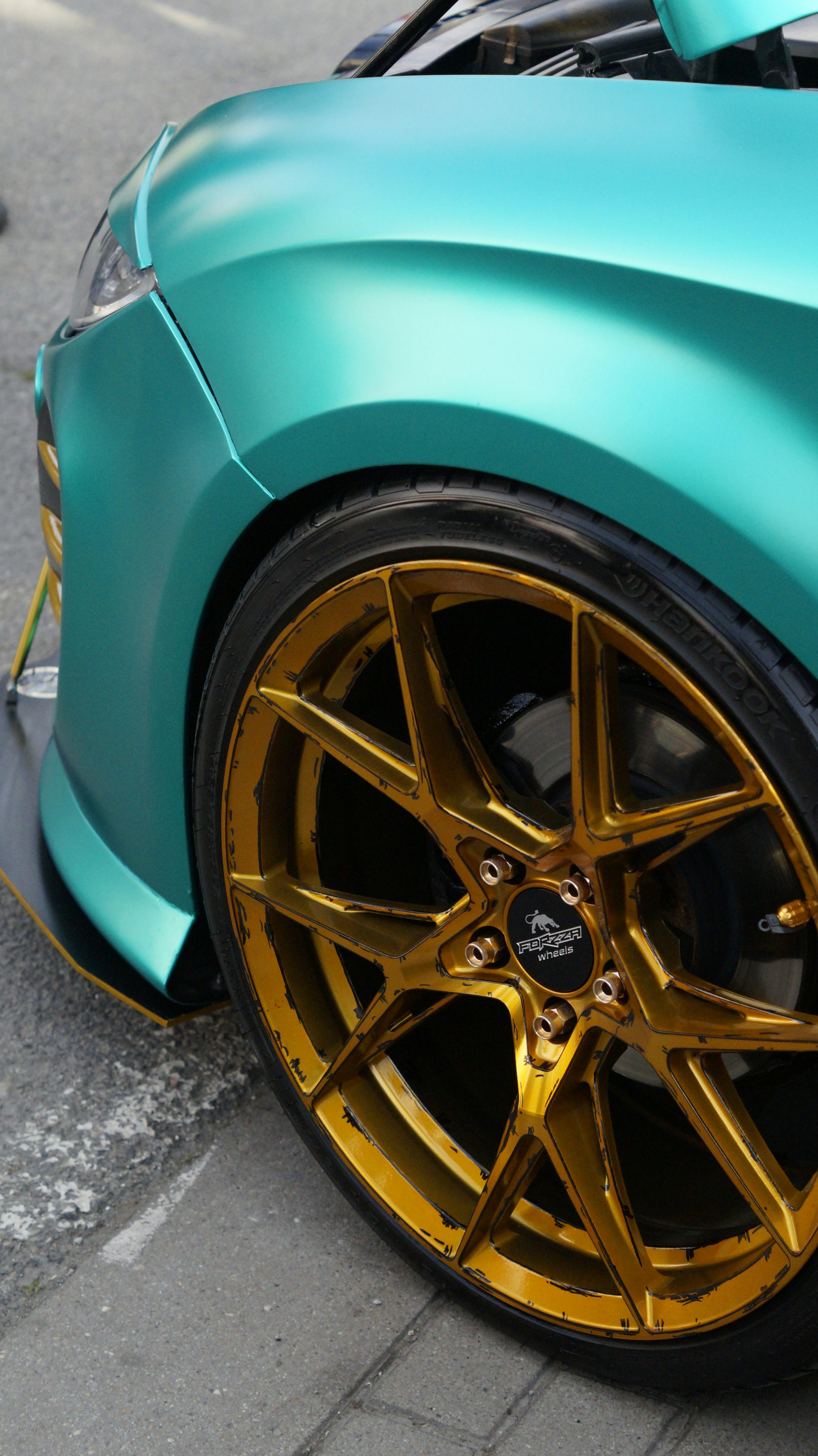 a blue sports car with gold rims parked on the side of the road