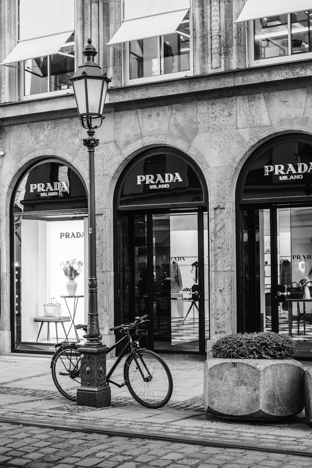 Una foto en blanco y negro de una bicicleta estacionada frente a una tienda Prada