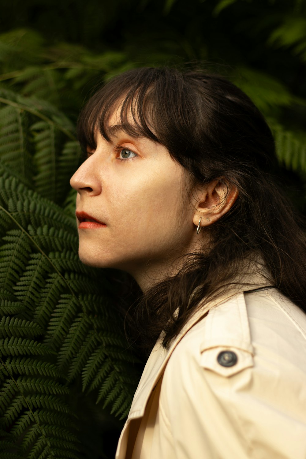 a woman standing in front of a green plant