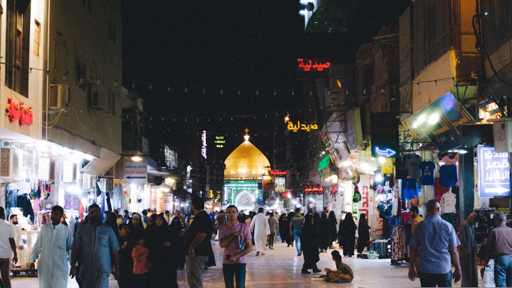 a crowd of people walking down a street at night