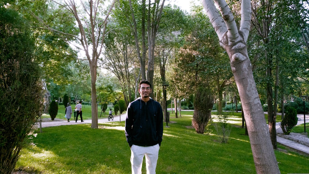 a man standing next to a tree in a park