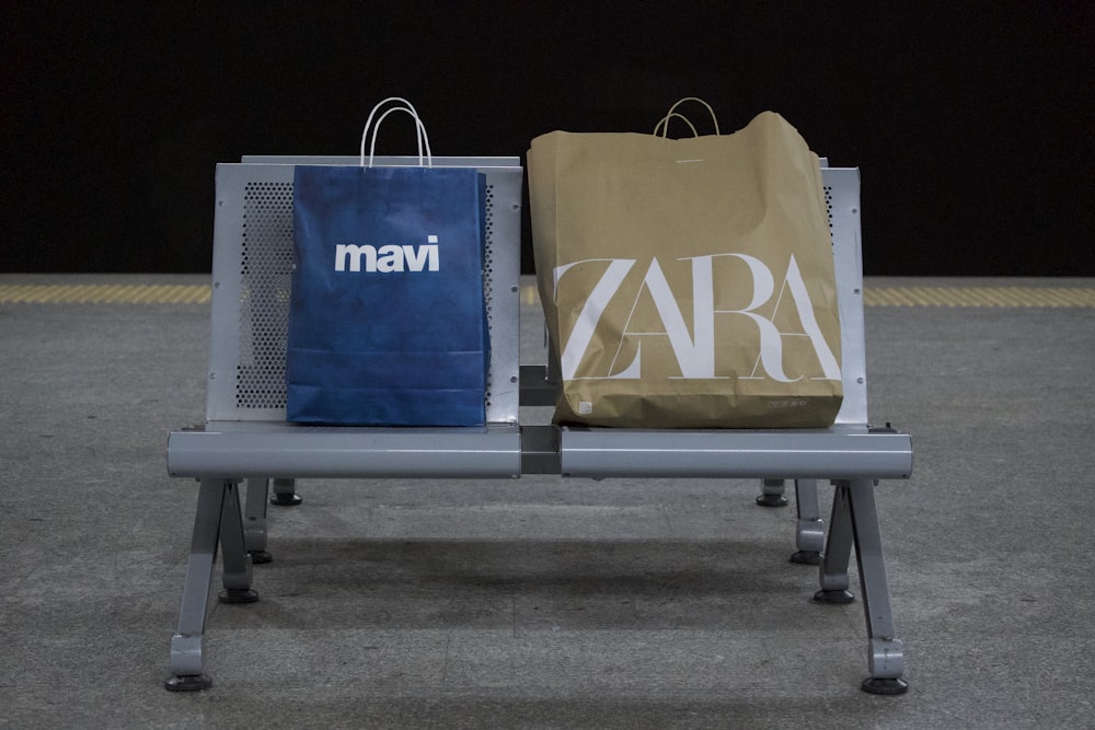 a couple of bags sitting on top of a metal bench