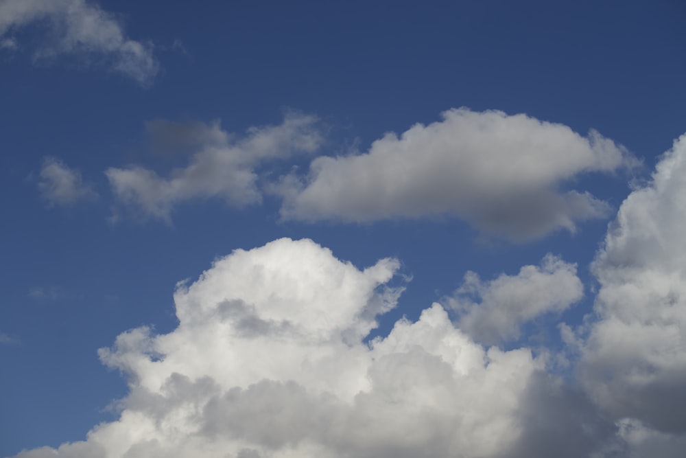 a plane flying through a cloudy blue sky