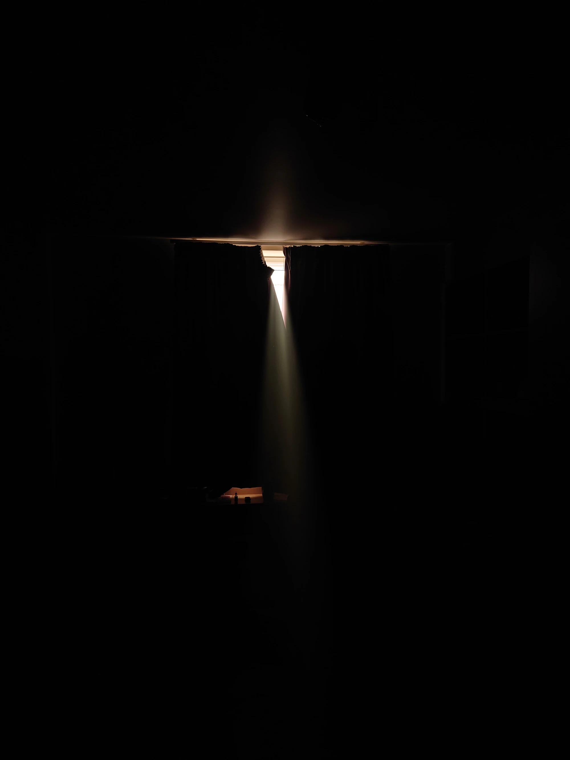 A dark room with a single shaft of light falling from an opening in the ceiling