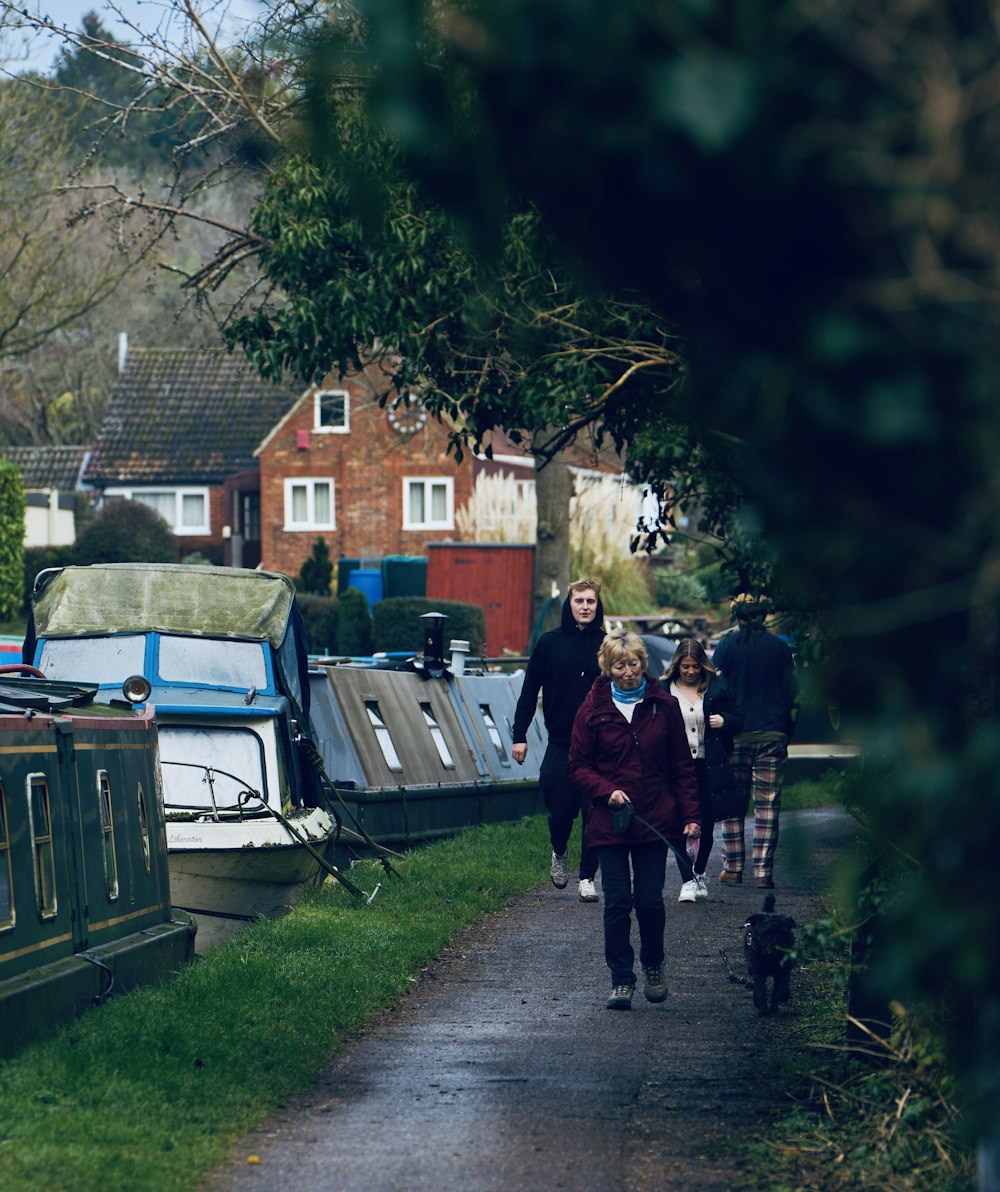 a group of people walking down a path next to boats