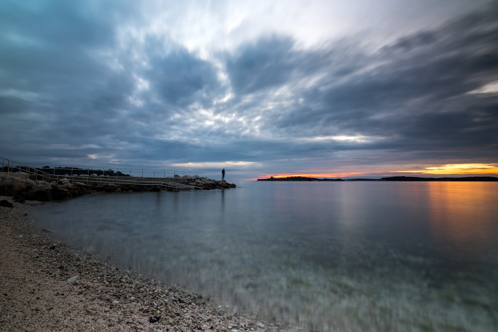 a body of water with a sky filled with clouds