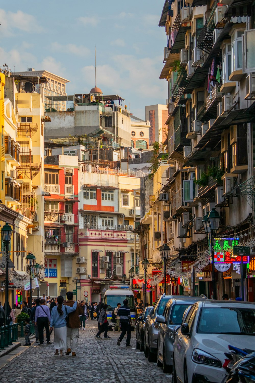 a group of people walking down a street next to tall buildings