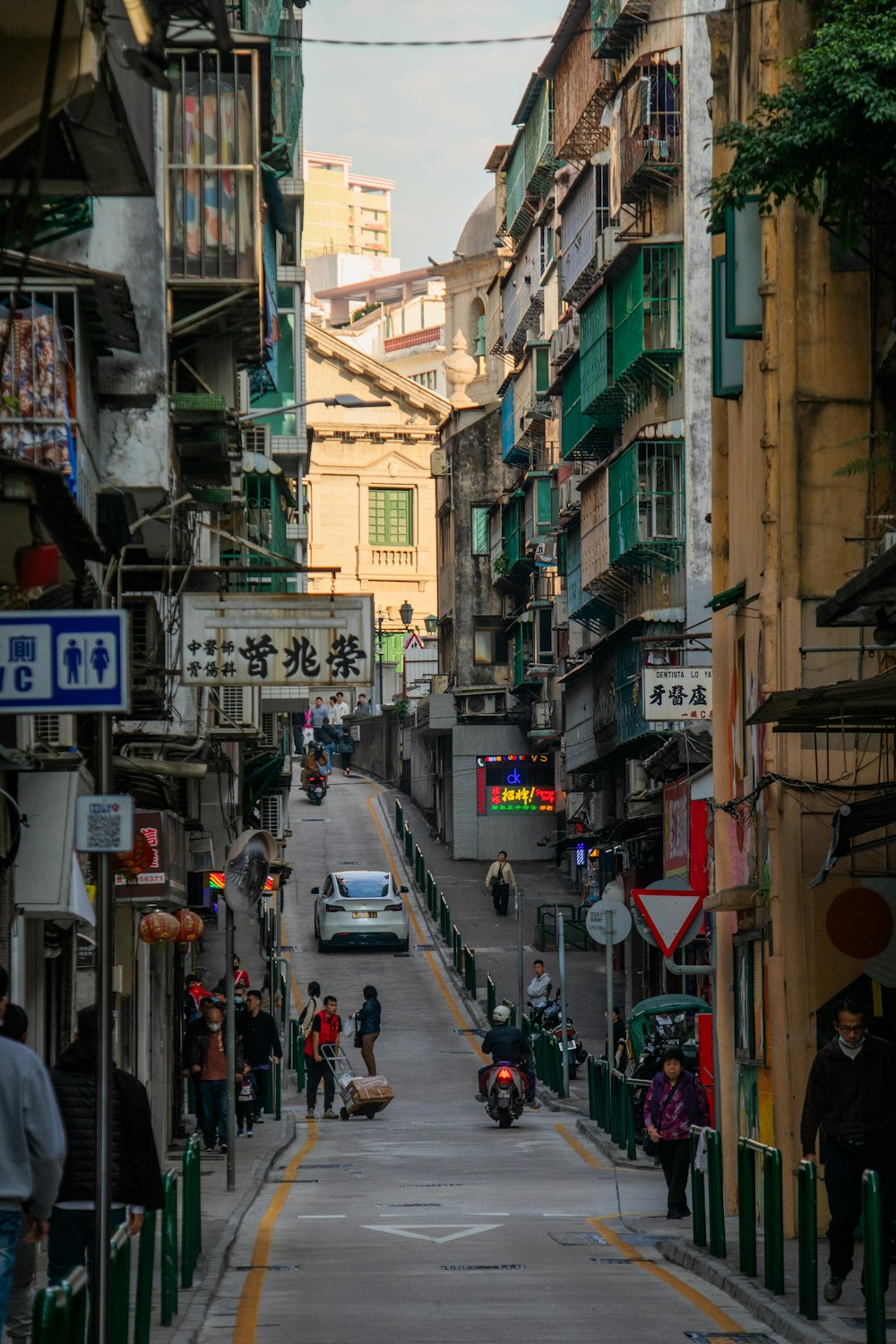 a narrow city street with people walking on the sidewalk