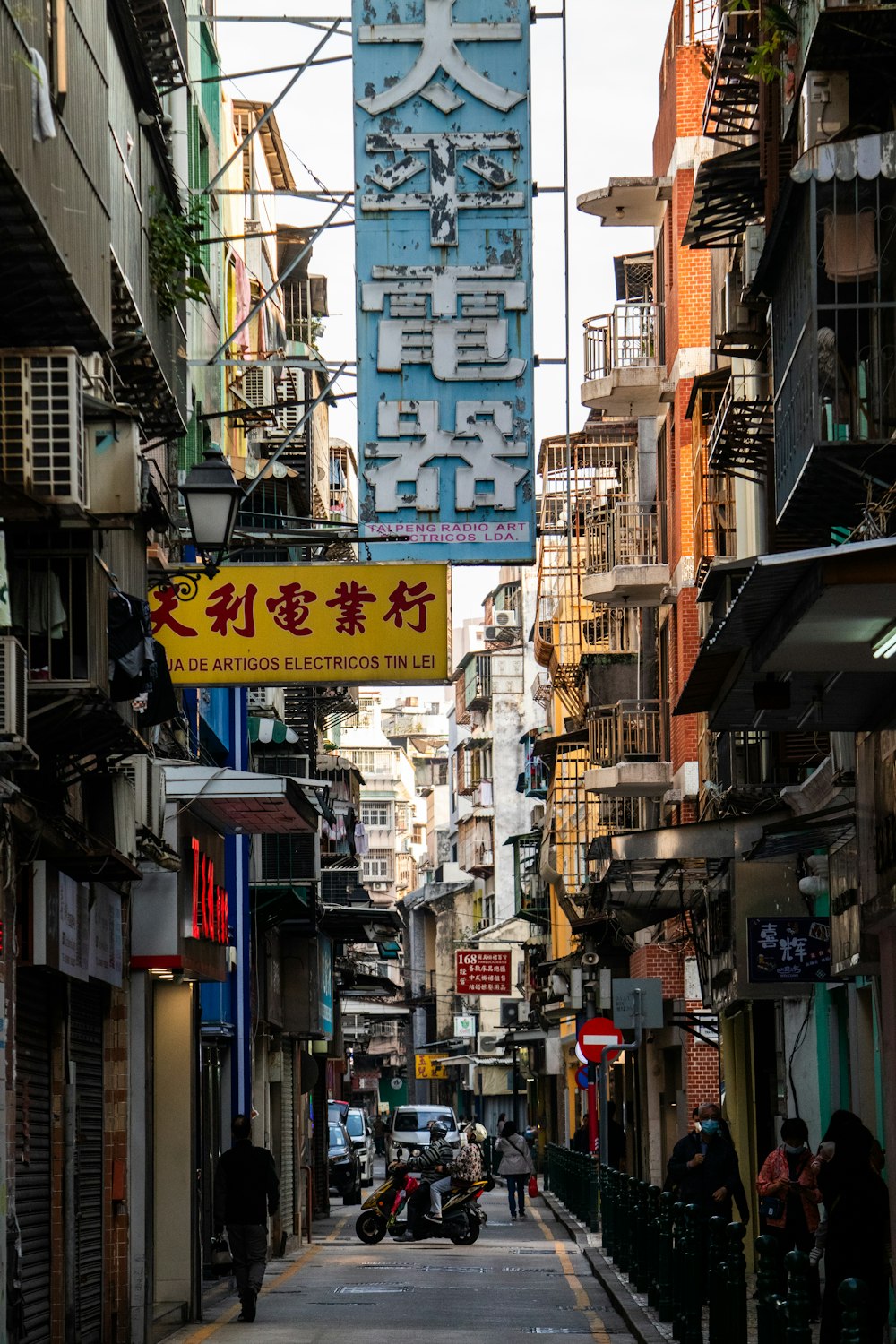 a narrow city street with a sign hanging from the side of it