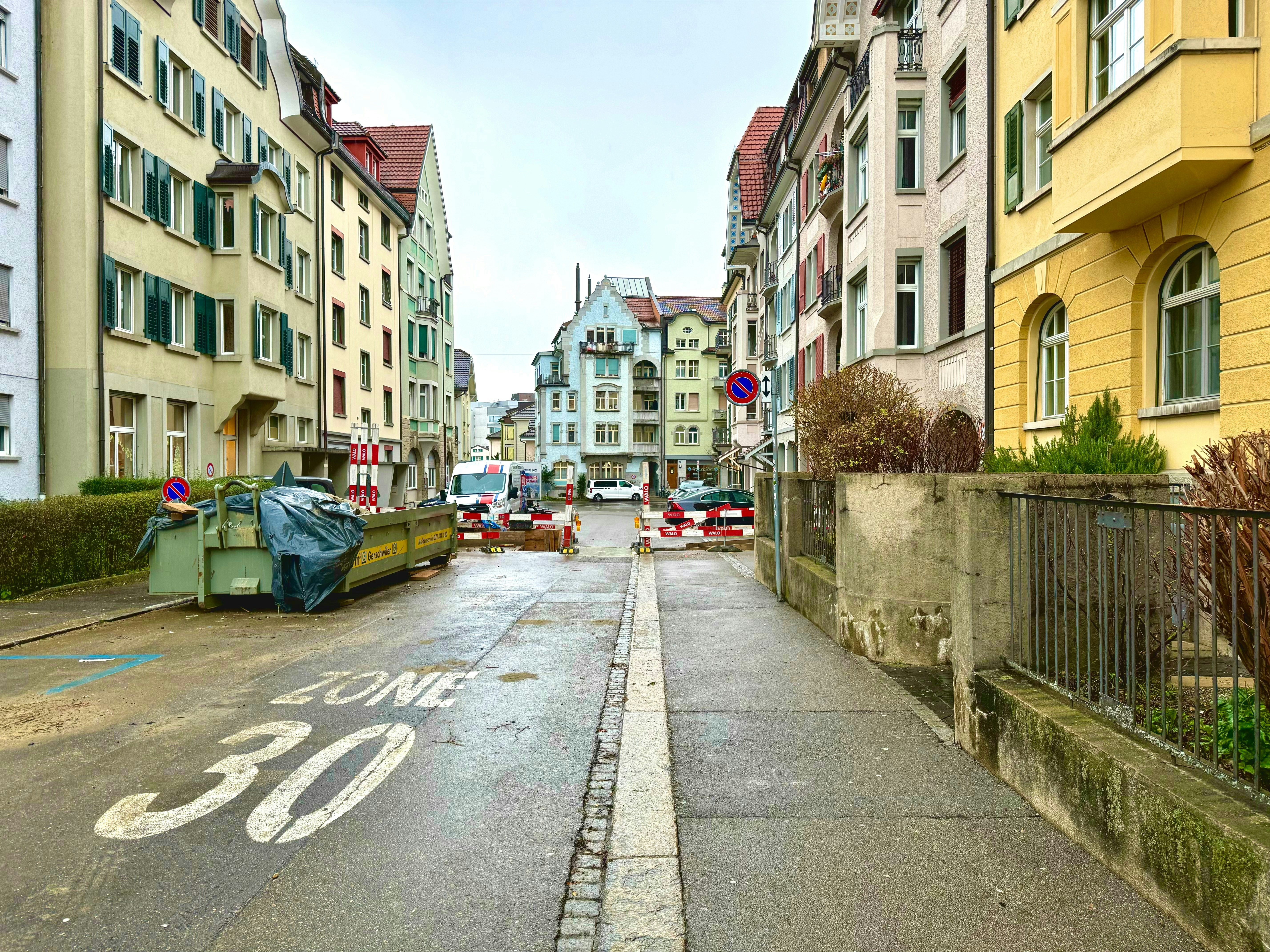 eine Stadtstraße mit Autos, die am Straßenrand parken