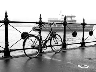 a bicycle parked next to a railing near a body of water