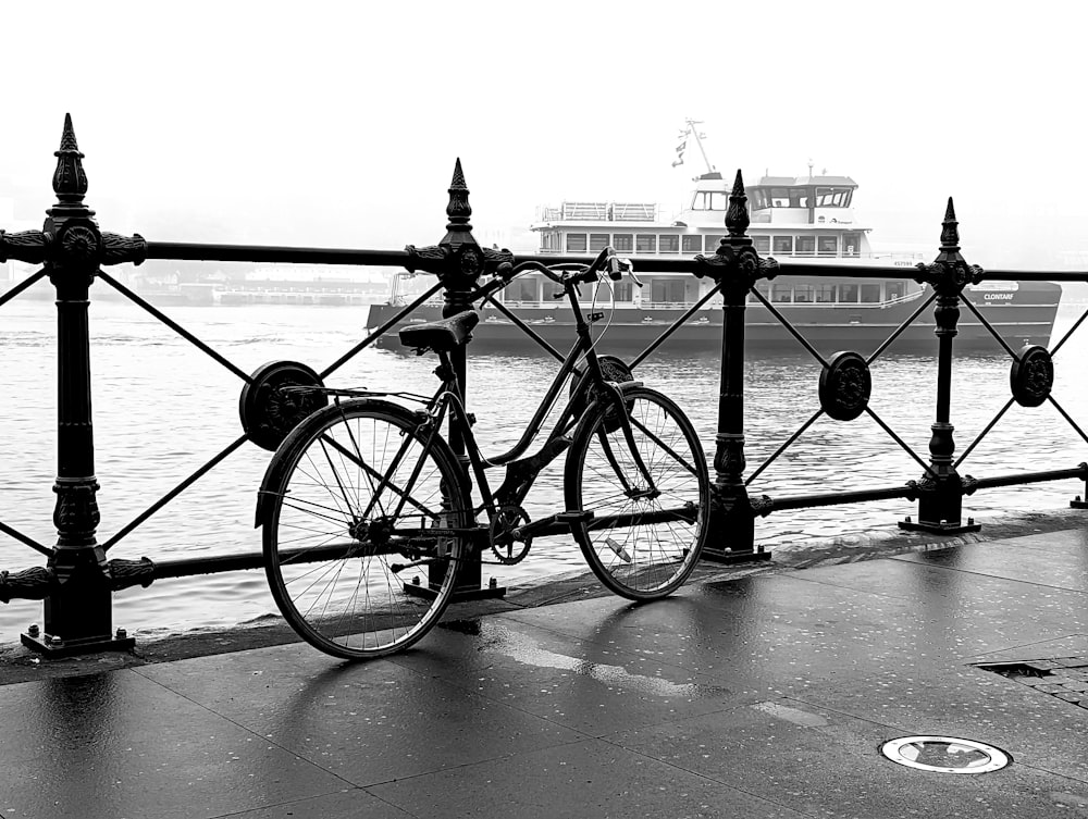 a bicycle parked next to a railing near a body of water