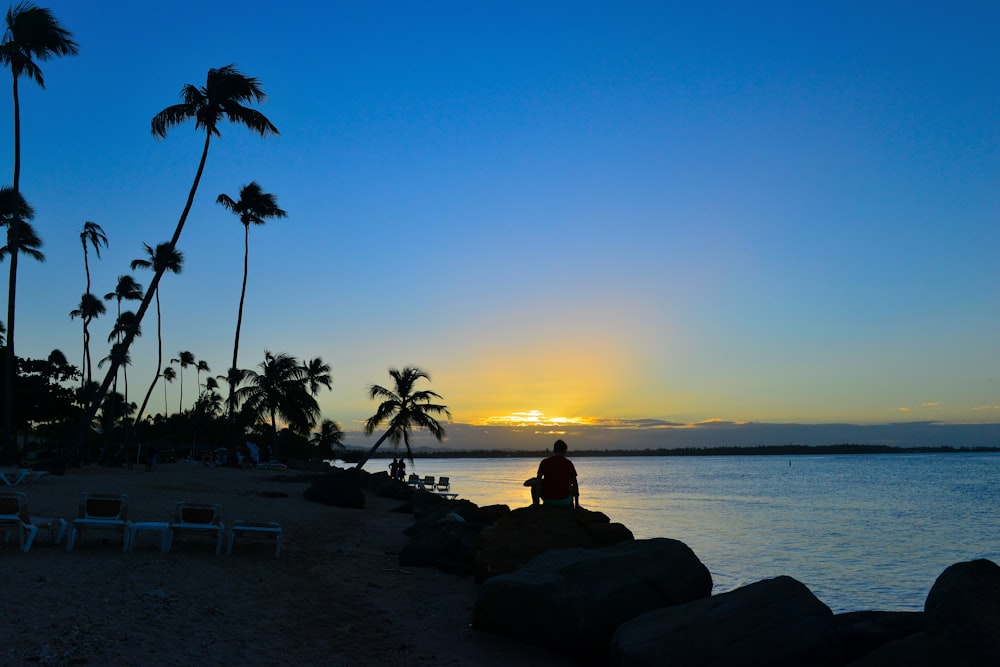 a person sitting on a rock near the ocean