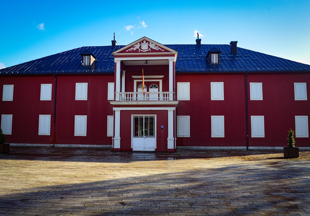 un bâtiment rouge avec des fenêtres blanches et un toit bleu