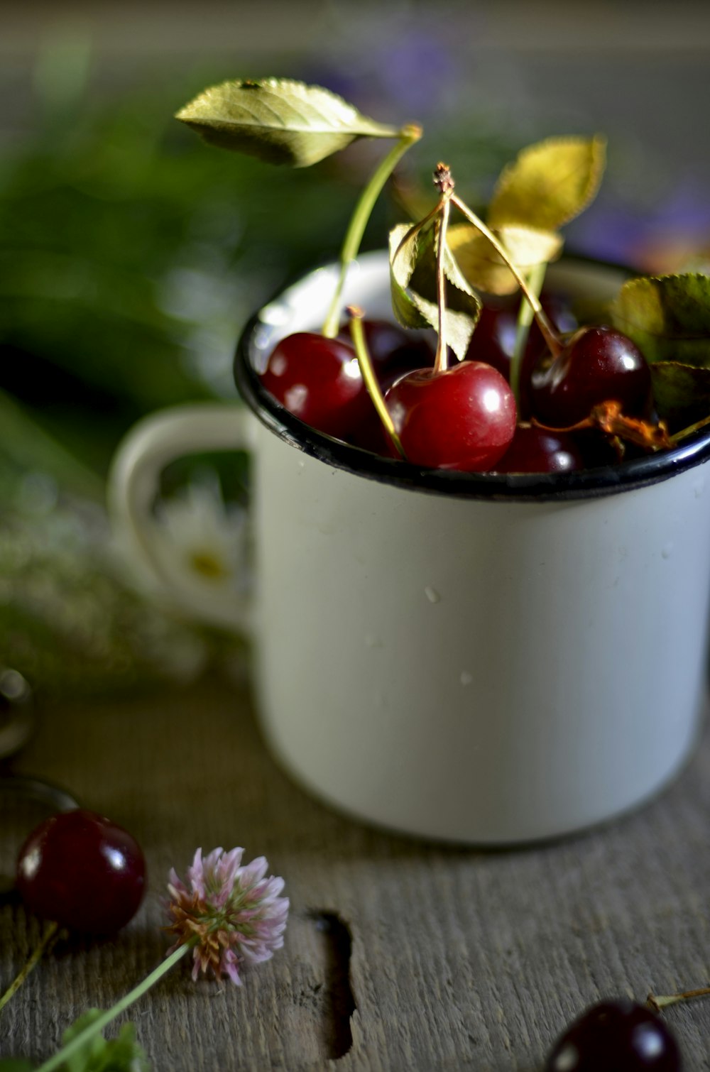 a white cup filled with cherries on top of a table