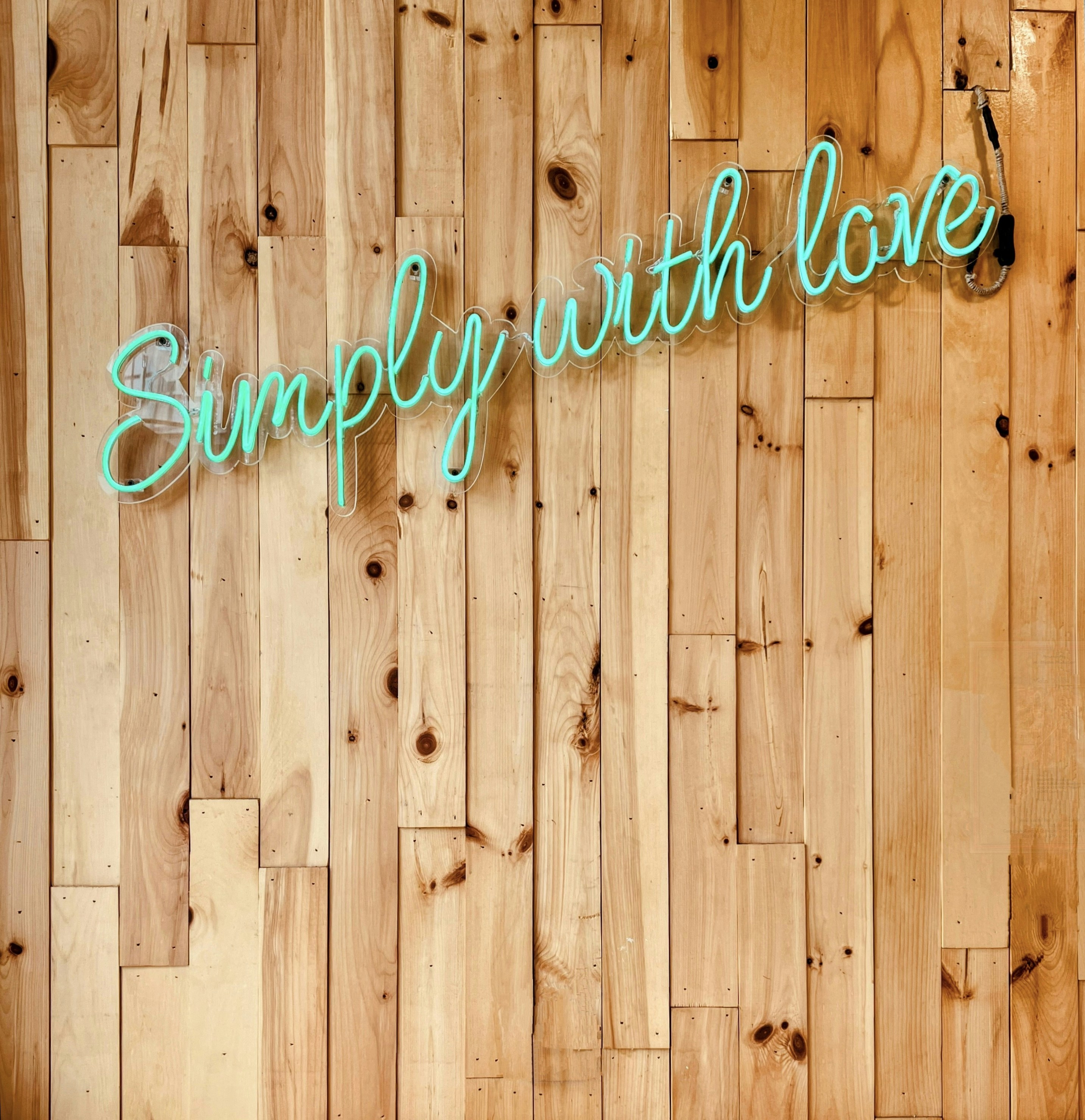 a wooden wall with a neon sign that says simply with love