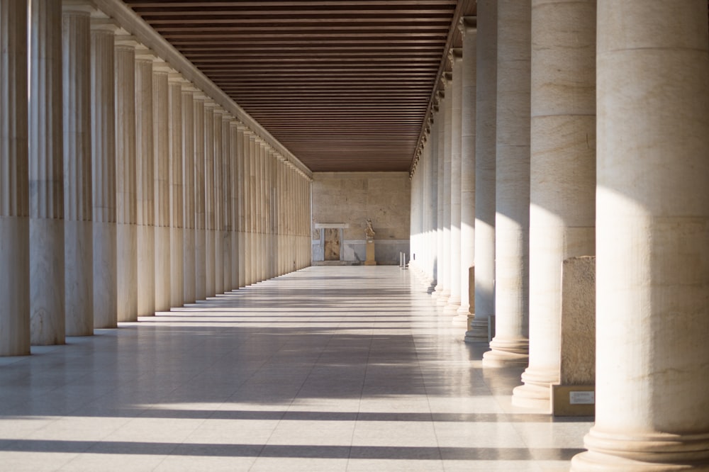 a long hallway with columns and a bench