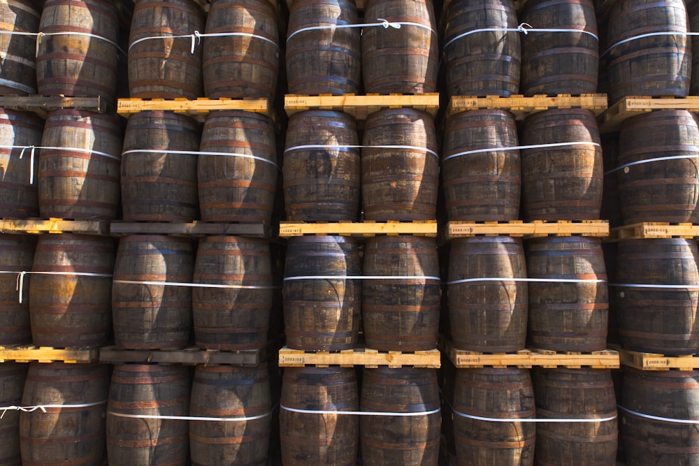 a large stack of wooden barrels in a warehouse