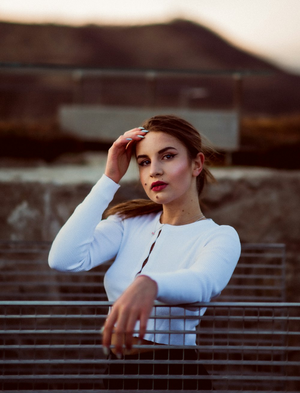 a woman in a white shirt leaning on a fence