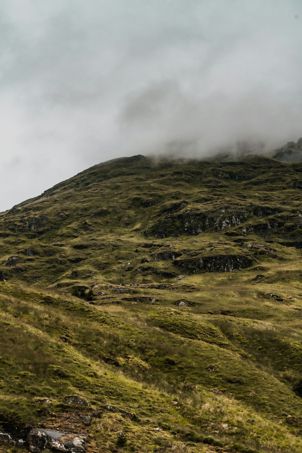 a grassy hill with a few clouds in the sky