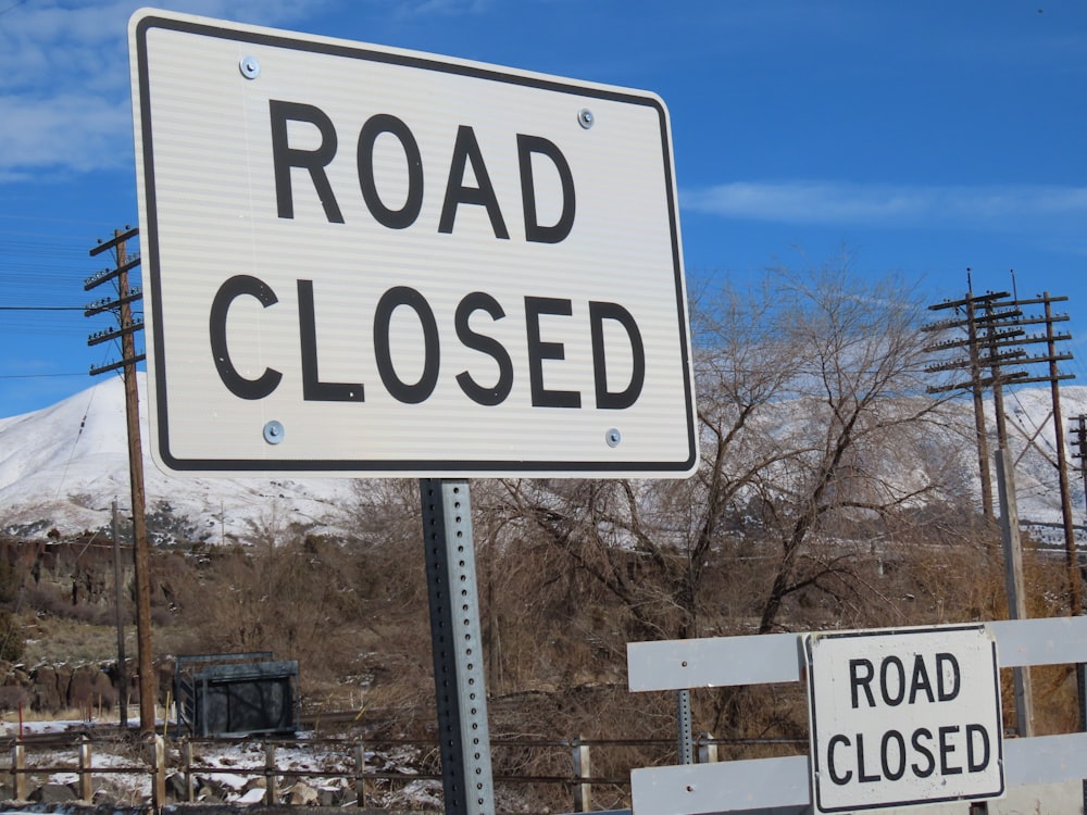 a road closed sign with a mountain in the background