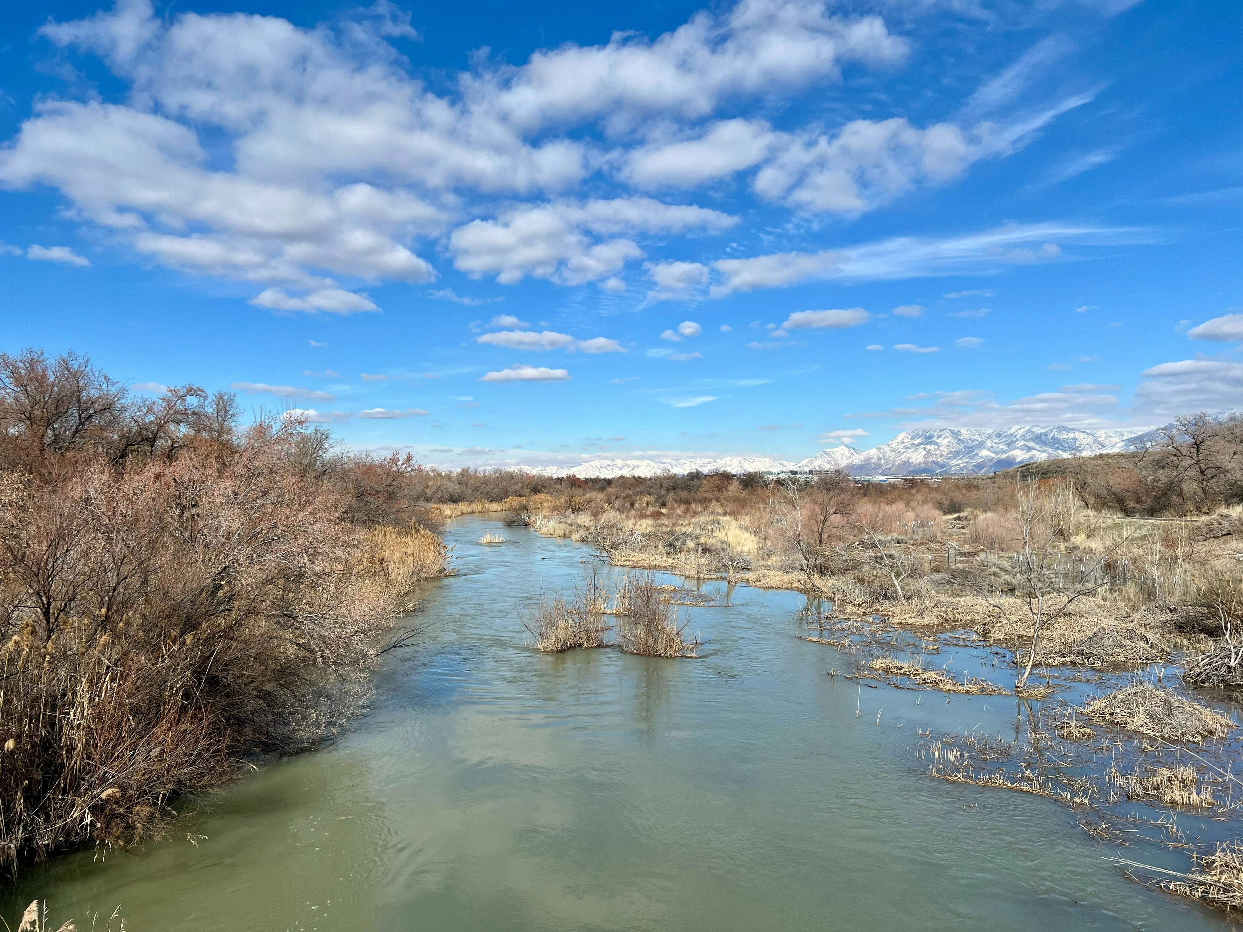 a river running through a dry grass covered field