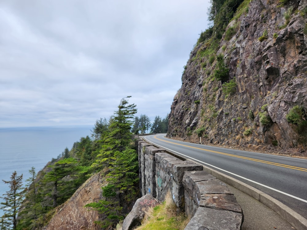 a road going down a mountain side next to the ocean