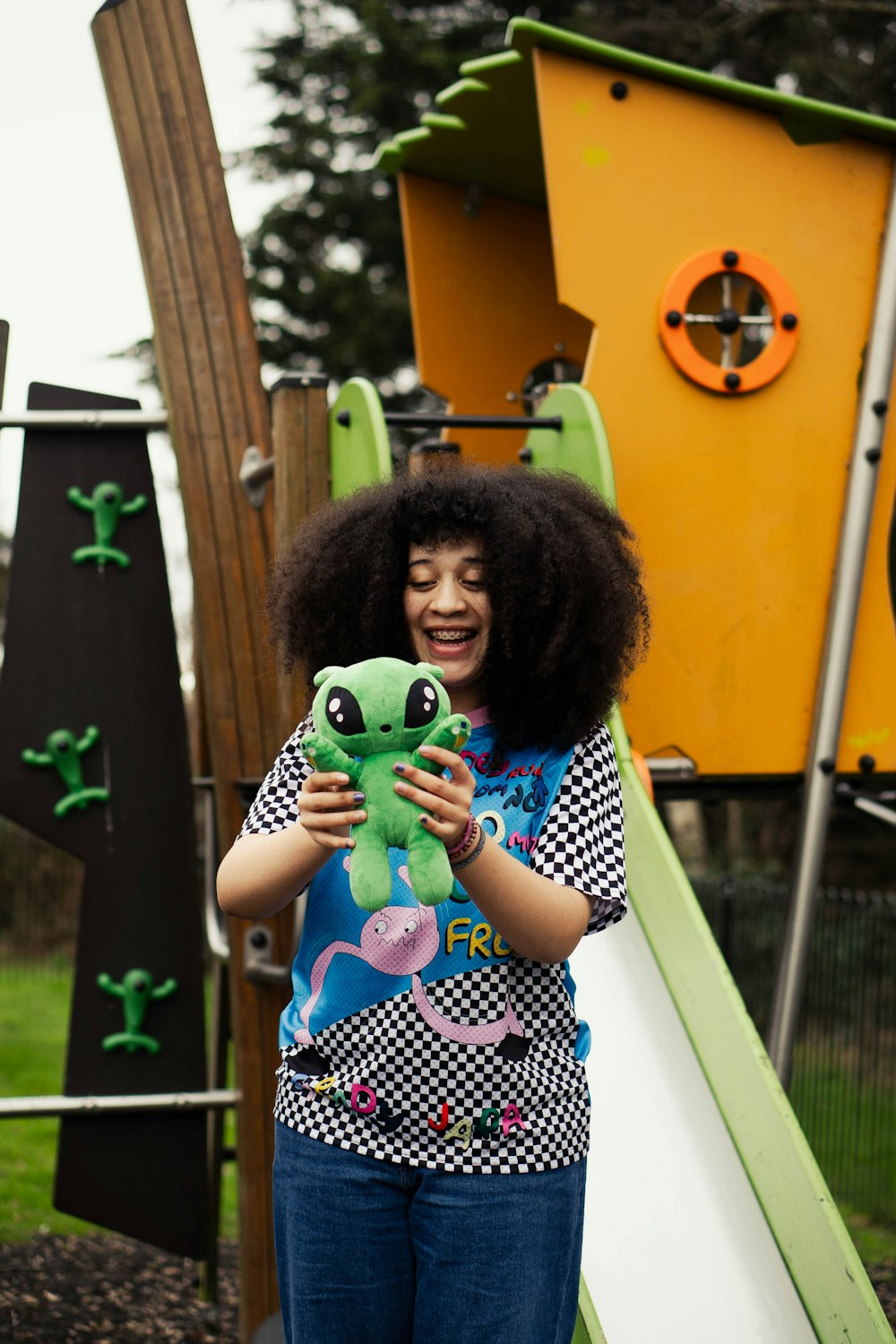 a woman holding a stuffed animal in front of a playground