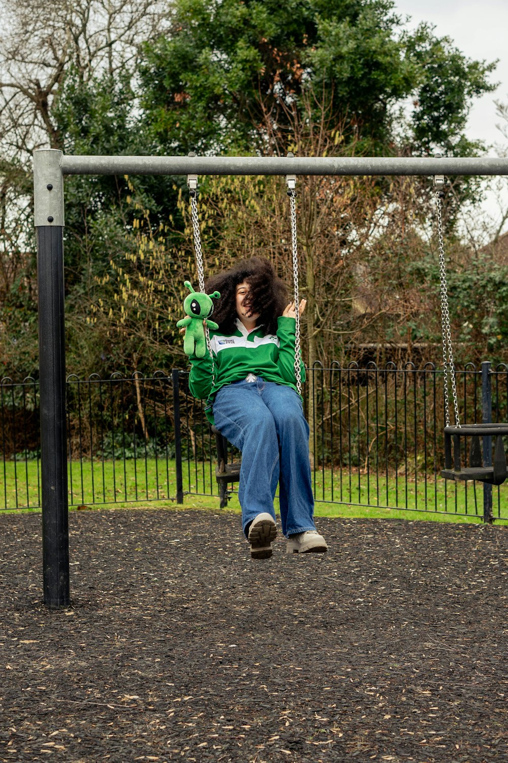 a woman sitting on a swing in a park