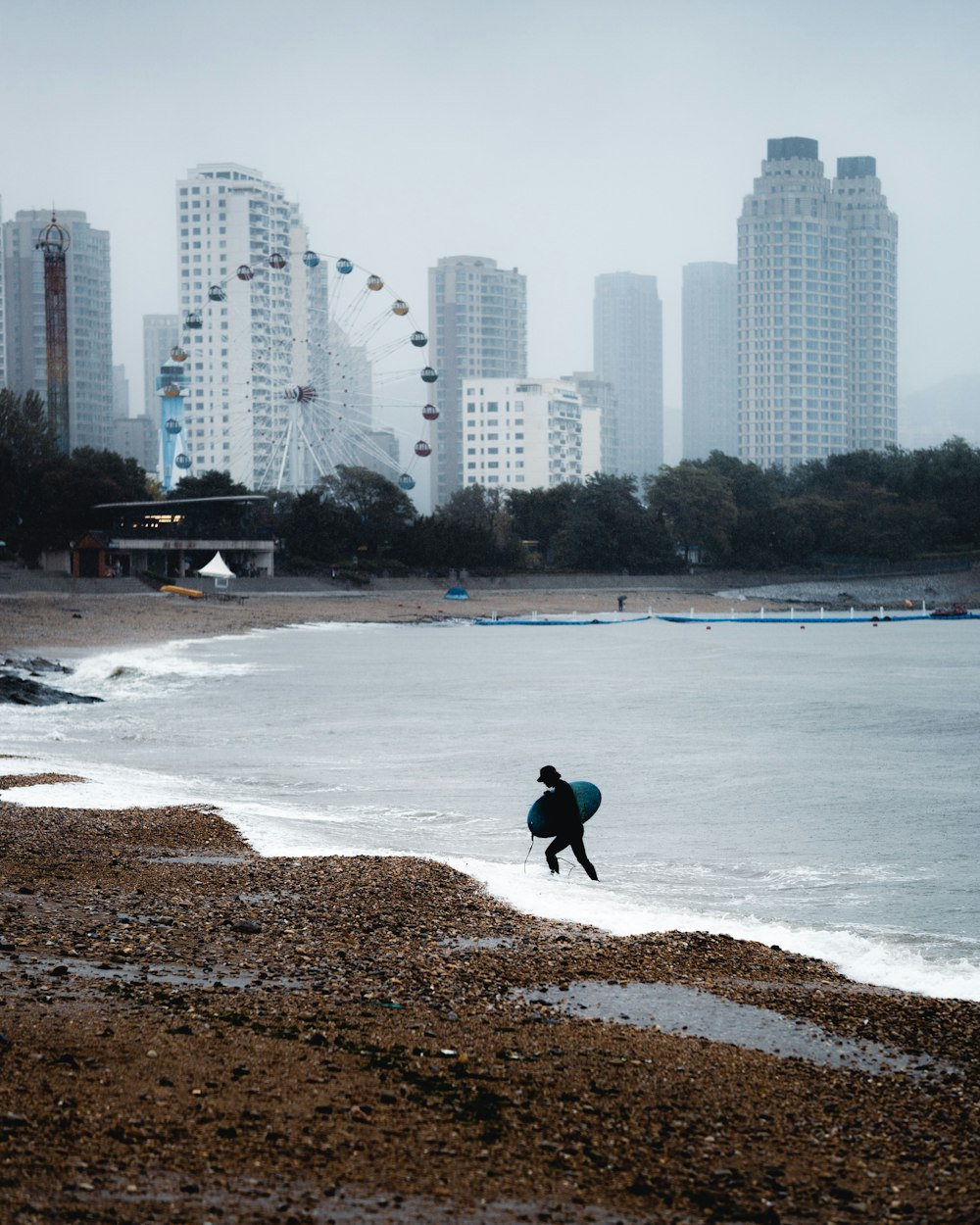um homem carregando uma prancha de surf em cima de uma praia de areia