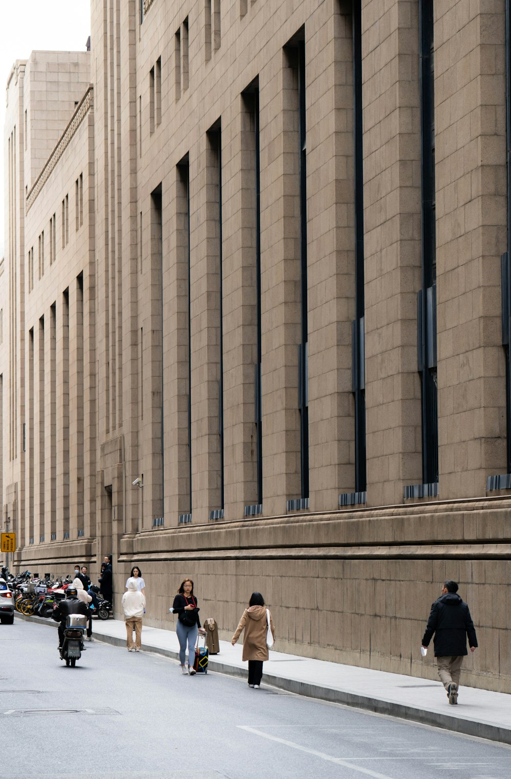 a group of people walking down a street next to tall buildings