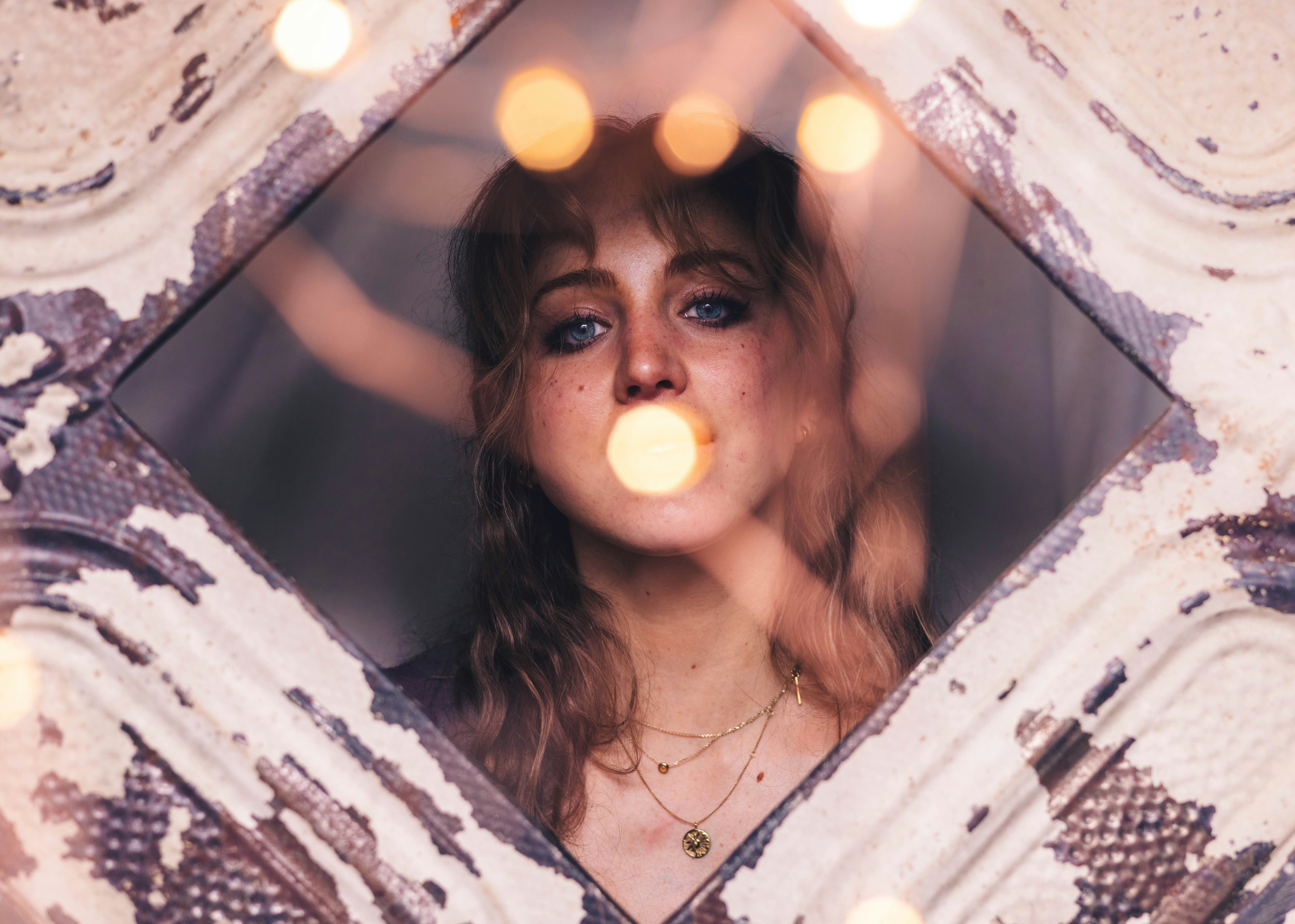 a woman with blue eyes looking through a window