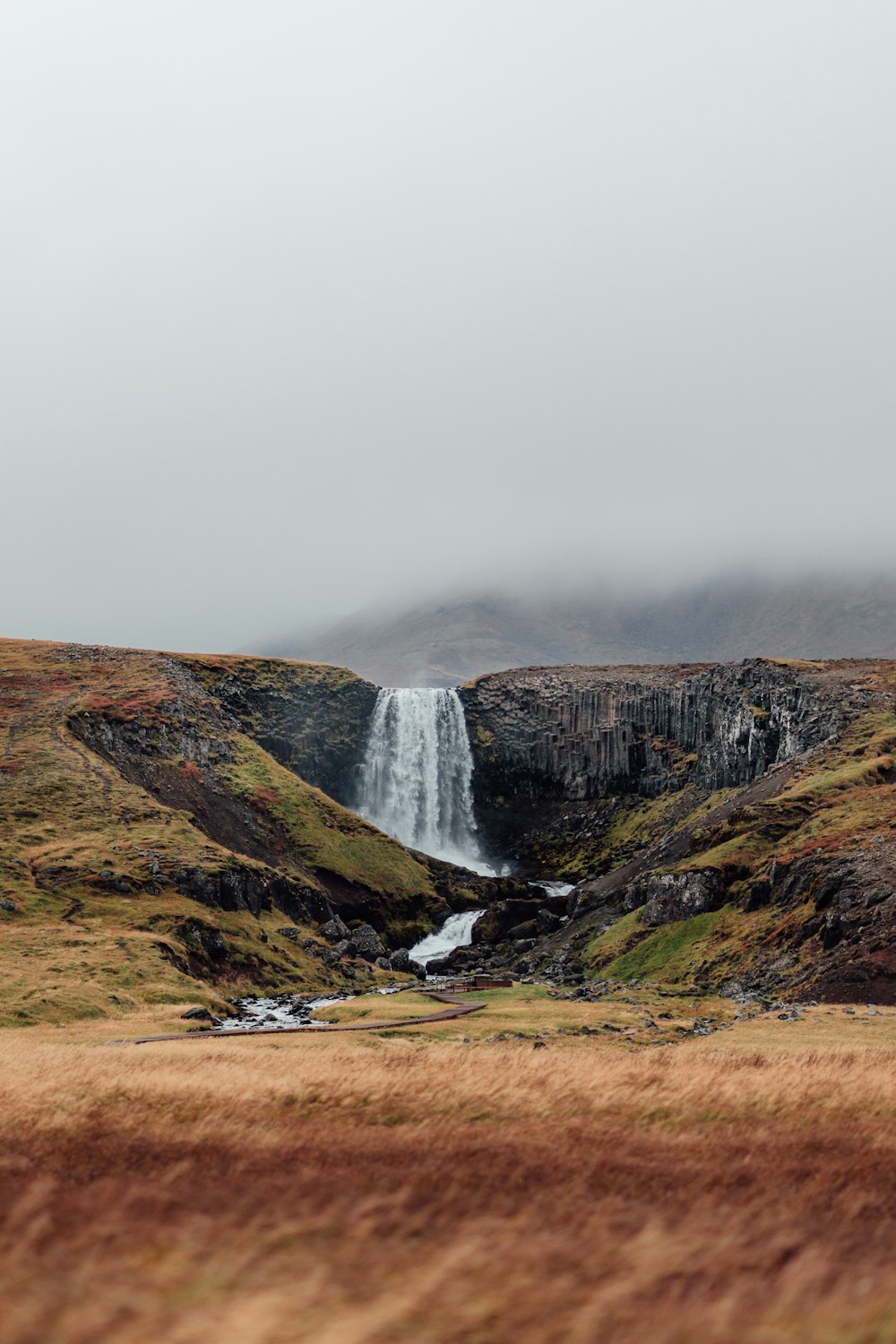 a waterfall in the middle of a grassy field