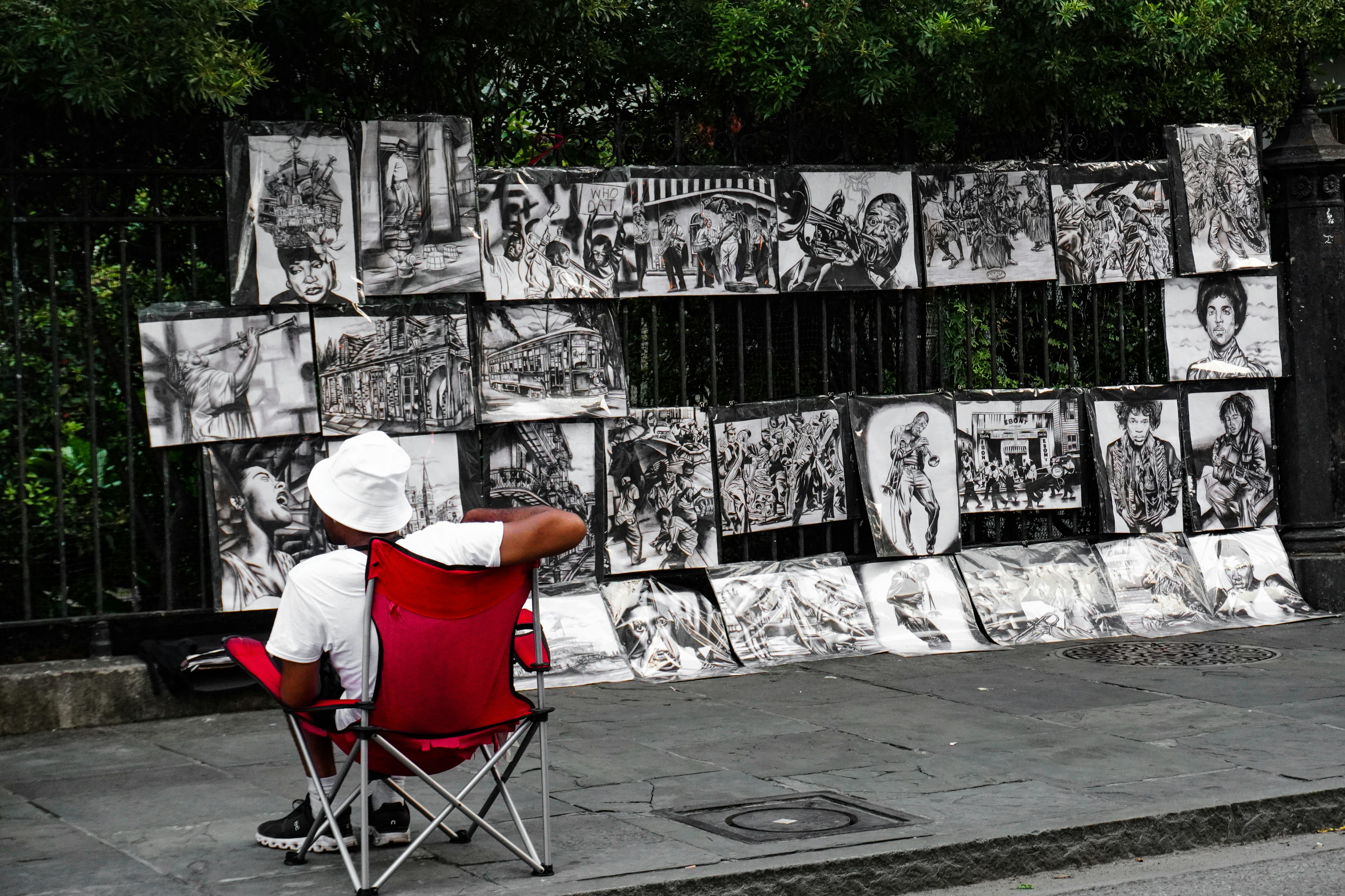 a man sitting in a red chair in front of a wall with pictures on it